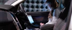 A person sitting in a car looking at its performance data on a laptop.