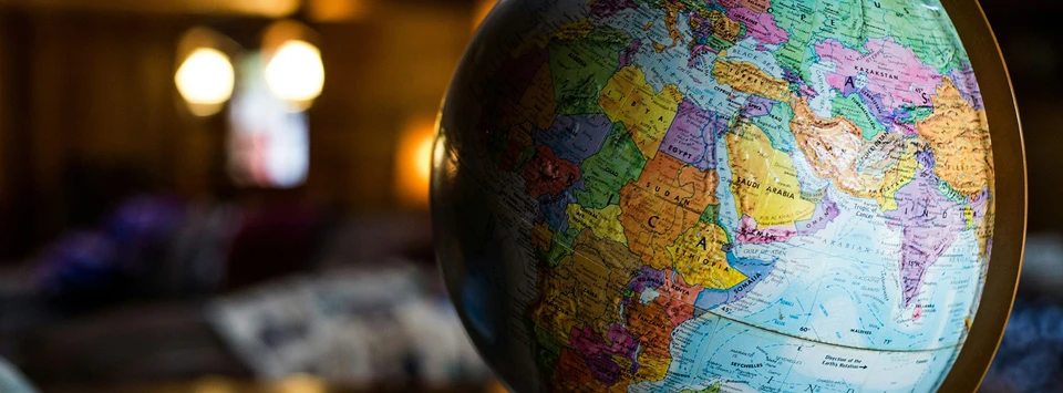 An old-fashioned spinning globe sits on a desk in a large room.
