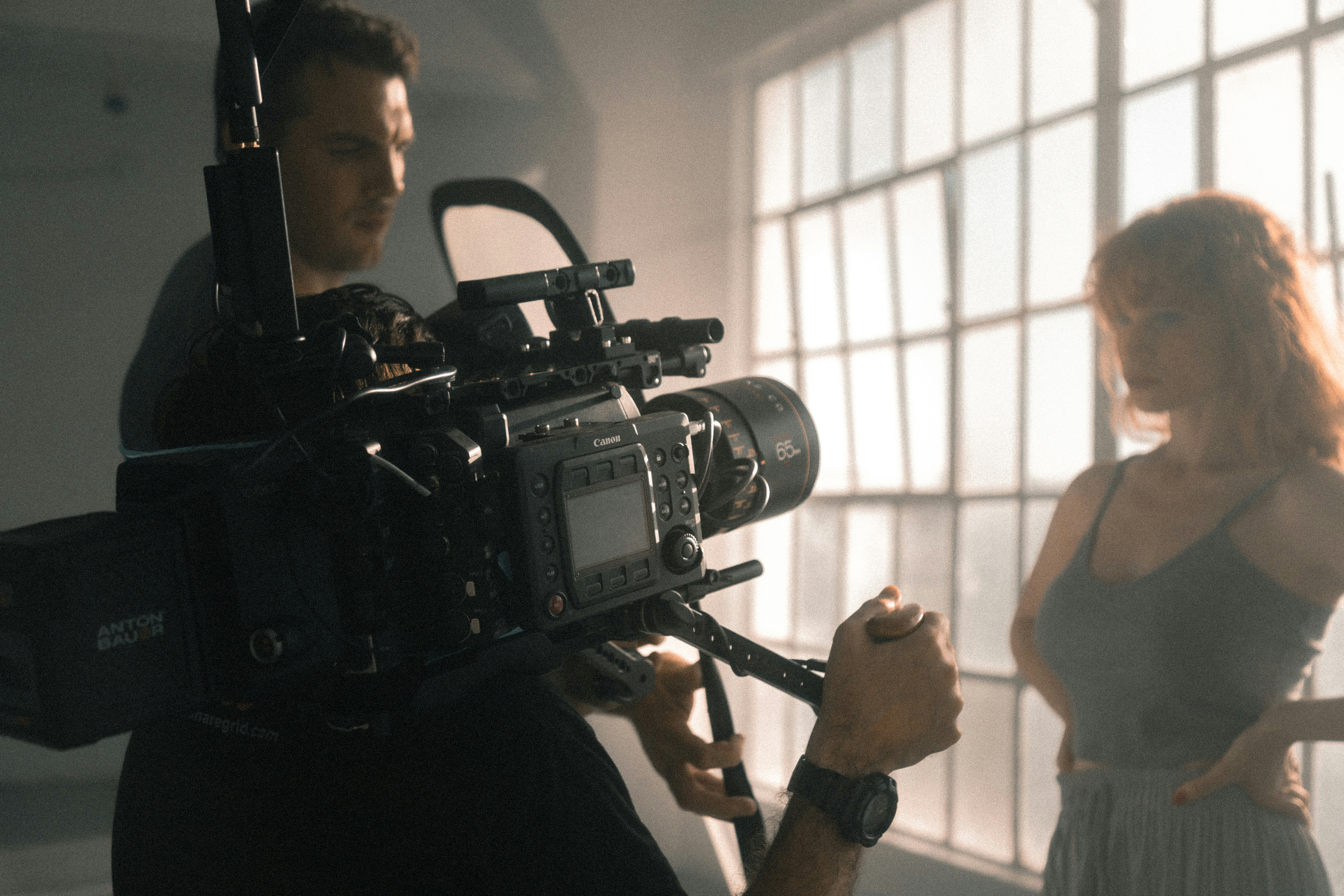 An actor is filmed in a moody room against a large bright window.