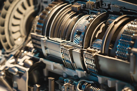 A close up of an exposed engine with lots of cogs on show.
