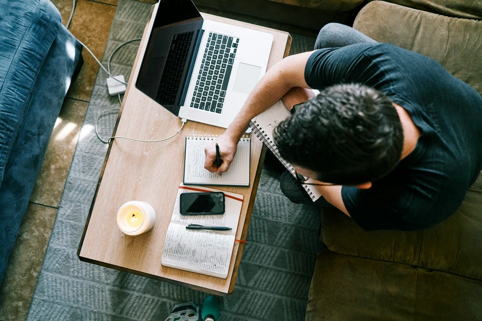 An overhead shot of someone working using a laptop at a desk.