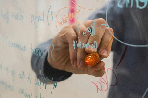 Someone writes on the other side of a see-through board.