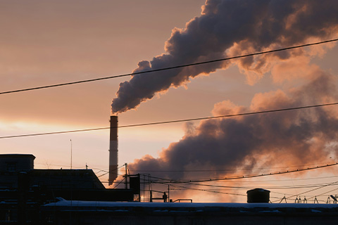 Silhouetted industrial smokestacks against a sunset.