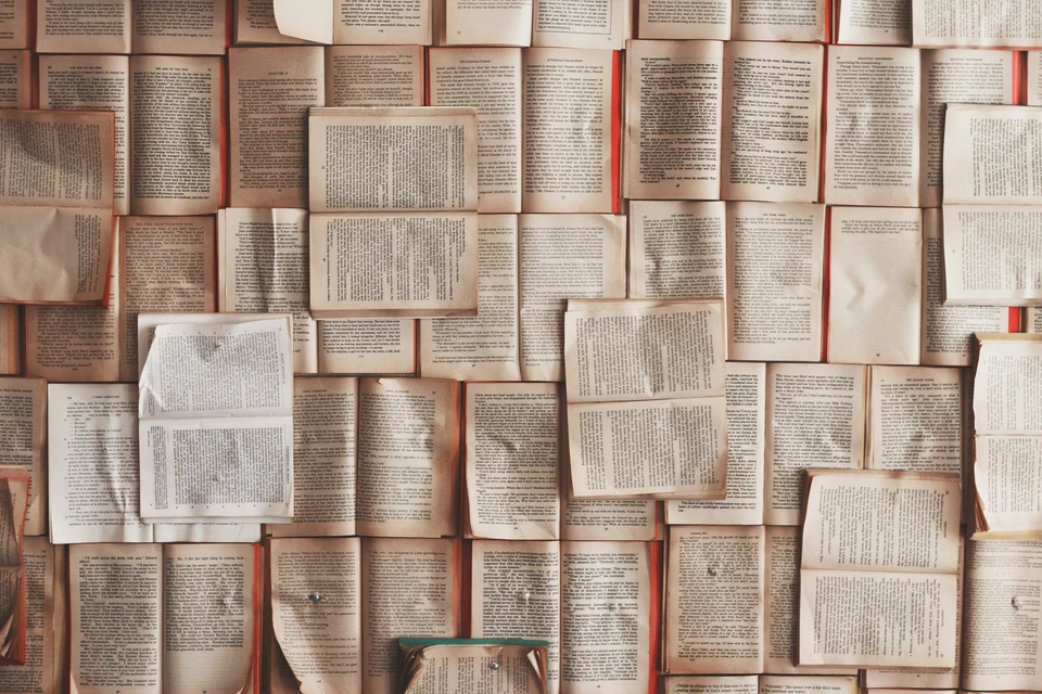 An overhead shot, looking down on many open books showing their text.