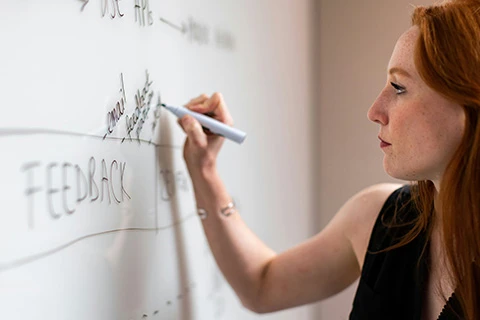 A developer adds stages to the feedback process on a whiteboard.