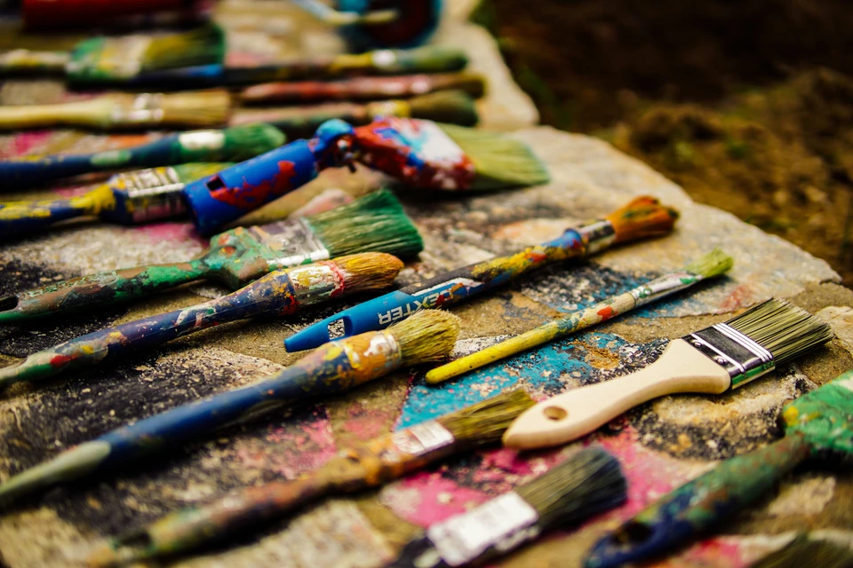 A selection of used brushes on an artist's palette.
