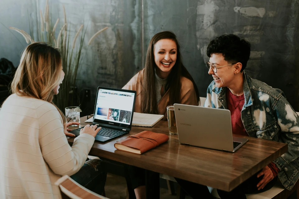 Three students working and laughing at table in a private study space.
