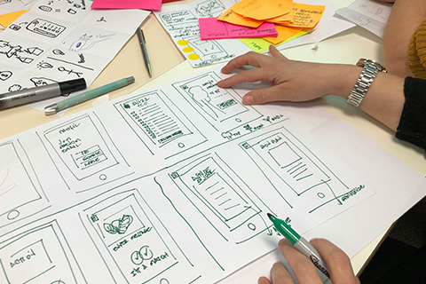 Someone drawing out different application screens on a large sheet of paper.