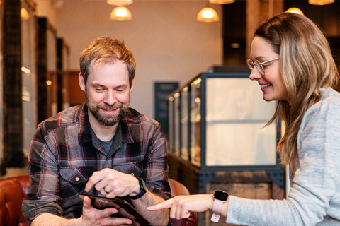 Two people looking at content on a tablet in a coffee shop.