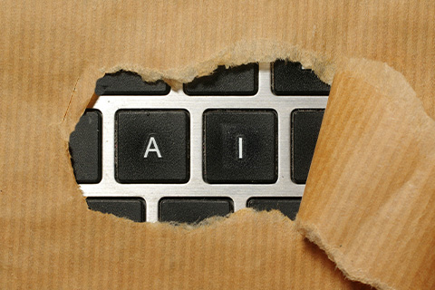 Brown wrapping paper torn back to reveal A and I on a keyboard.