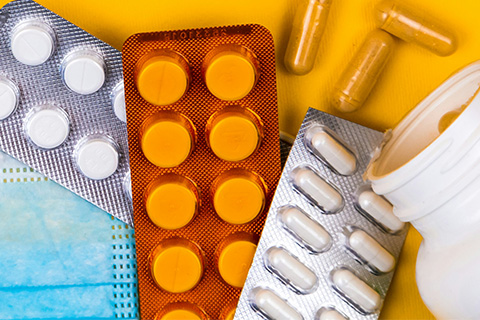 A selection of pills in blister packs on top of a blue mask.