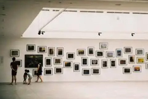 A family admire paintings on a large wall.